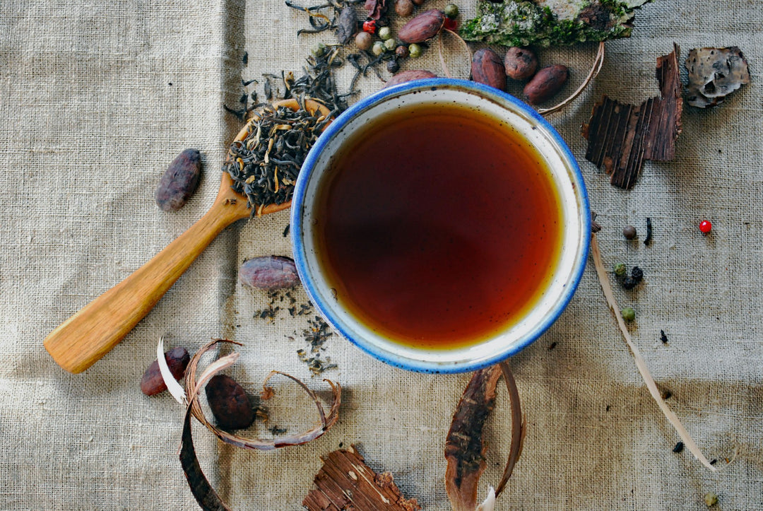 A cup of wellness tea surrounded by herbal ingredients 