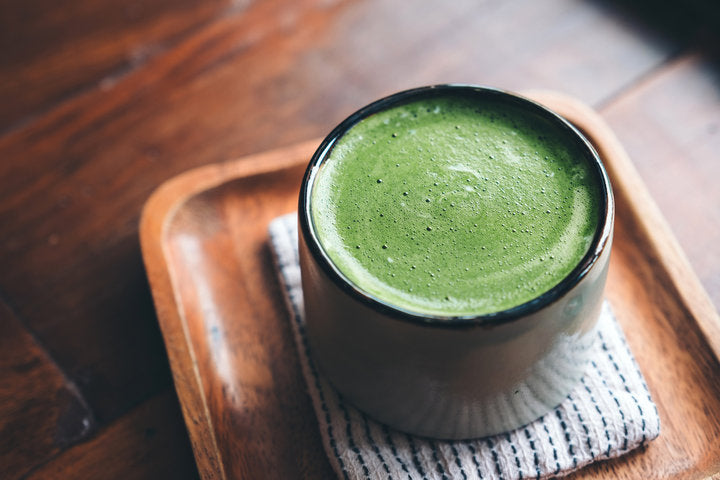 A frothy matcha latte made with organic matcha green tea powder in a modern kitchen setting.