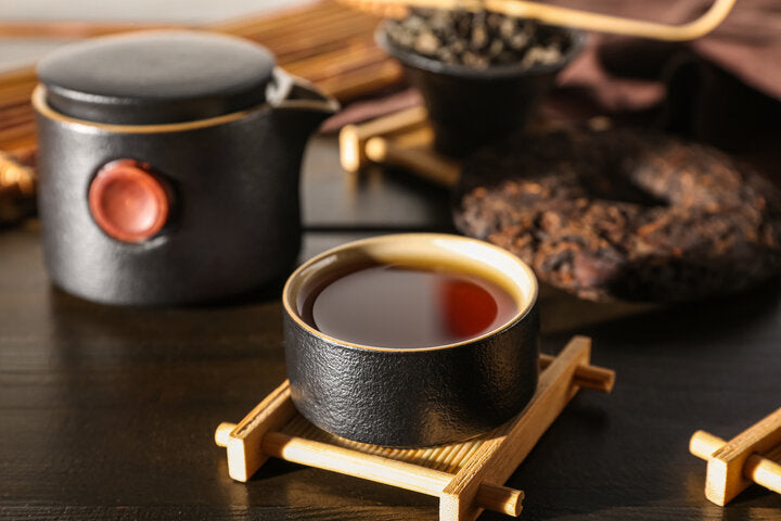 Premium organic Lapsang Souchong loose leaf black tea leaves displayed in a small black ceramic bowl.
